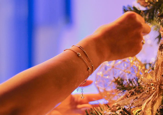 Mano con pulseras de oro decorando un árbol de navidad