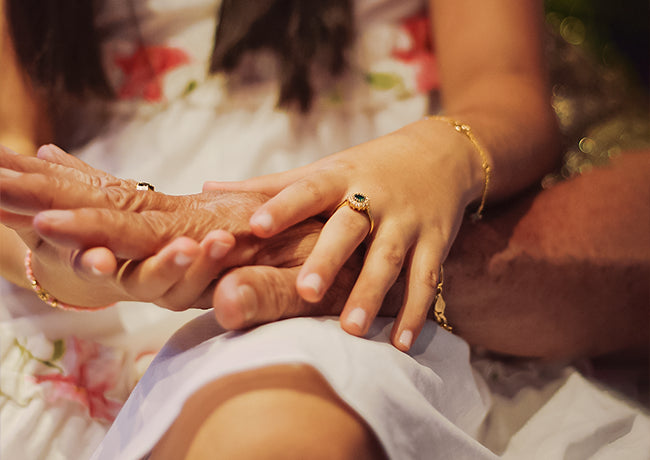 Mano de niña sosteniendo Mano de su abuelo con joyas de oro 